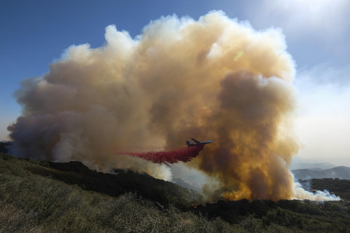 An air tanker drops retardant on a wildfire.