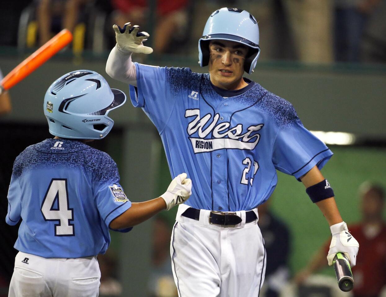acob Baptista (23) celebrates with Cameron Barbabosa (4) after scoring on a hit by Dante Schmid during the first inning.