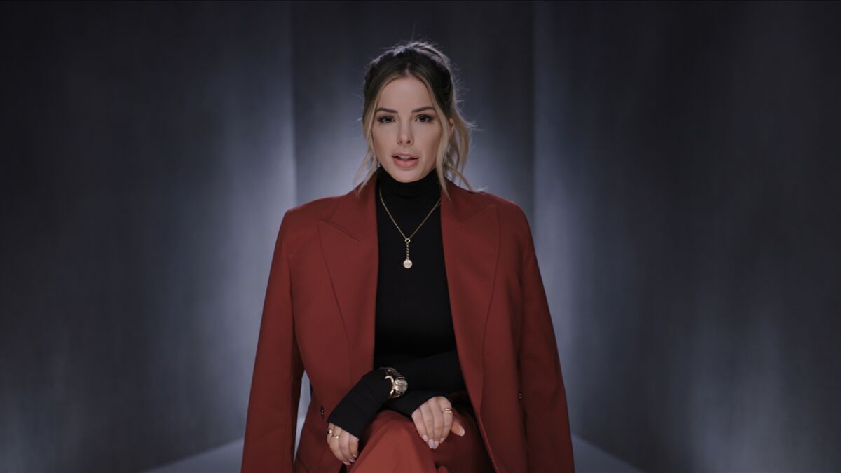 A woman wearing a black turtleneck and burgundy jacket 