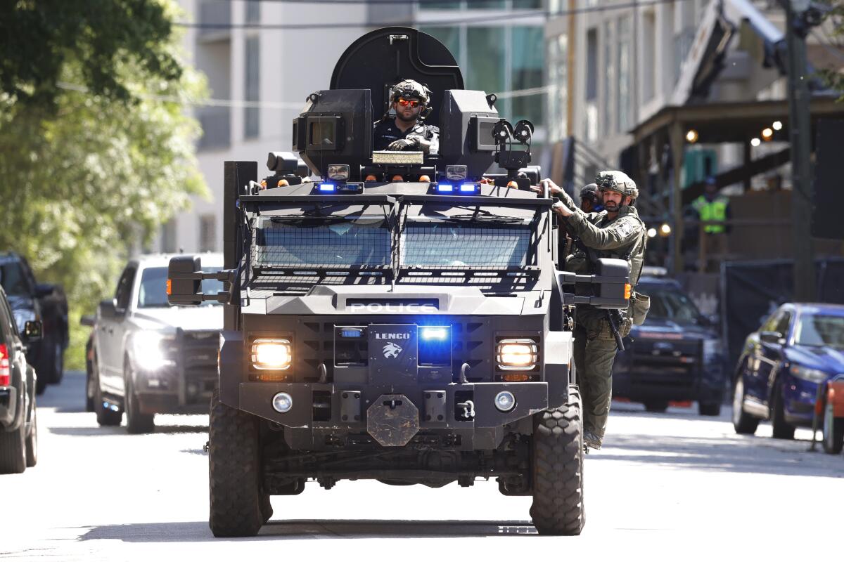 
Uniformed officers are seen on an armored vehicle near buildings 