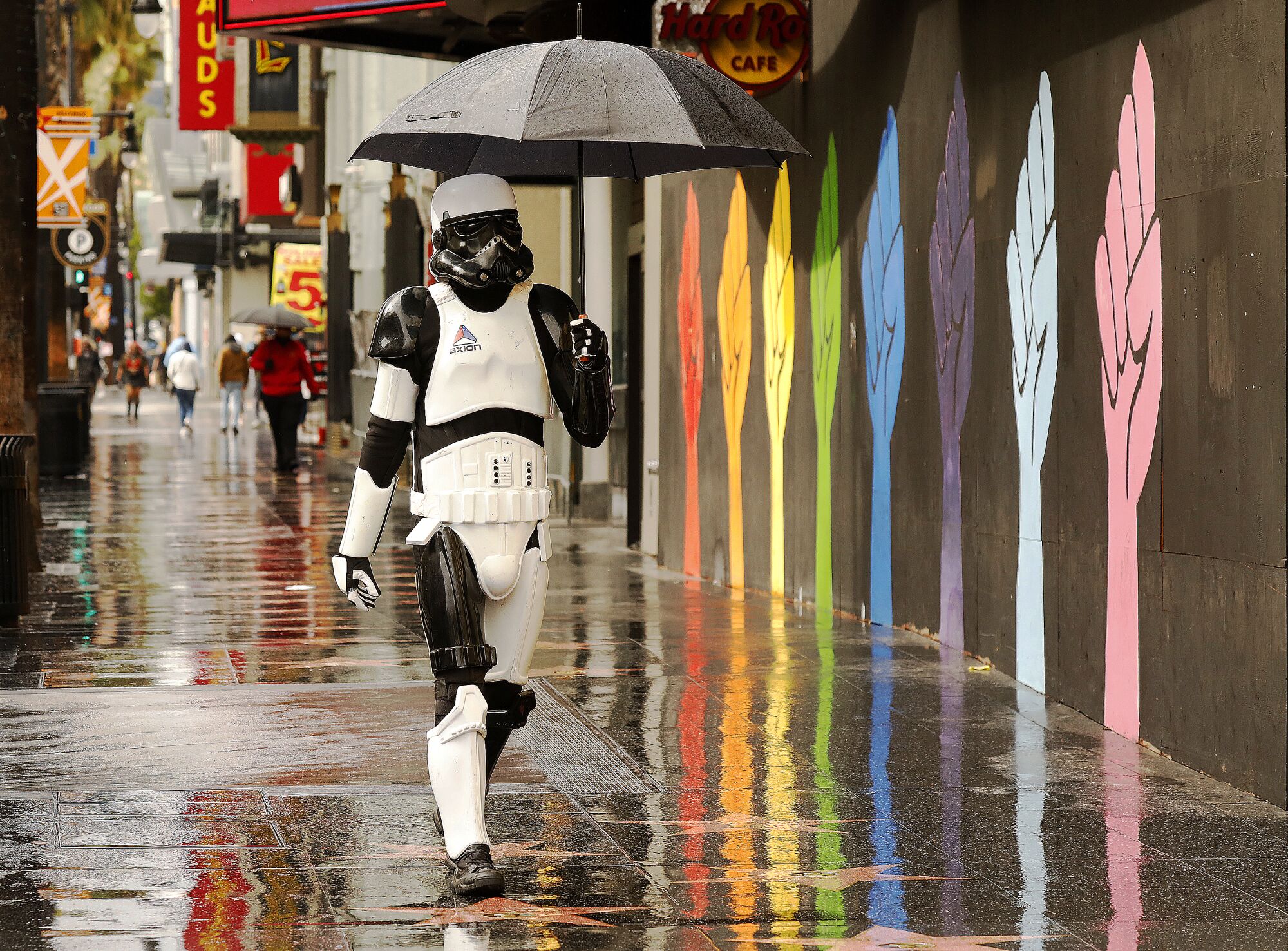 A costumed stormtrooper walks under an umbrella on Hollywood Boulevard.