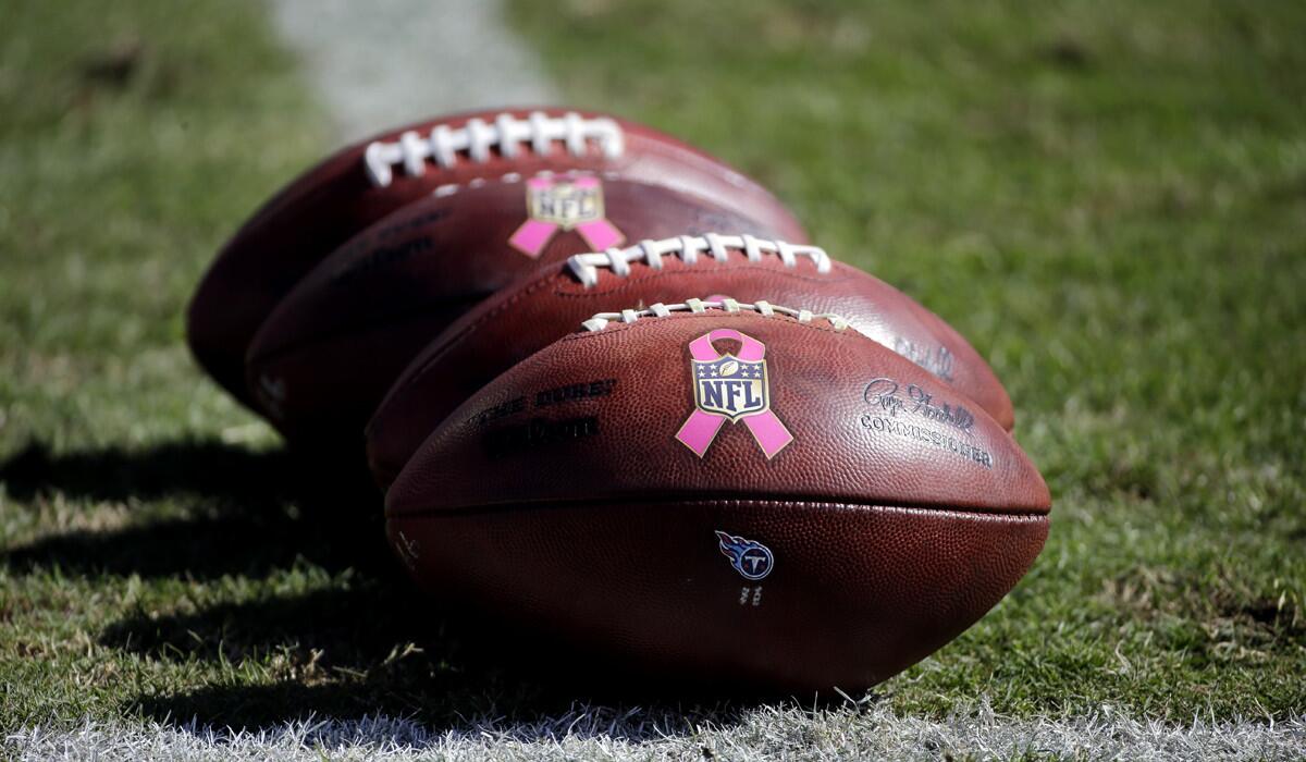 Footballs with breast cancer awareness logos sit on the field before a game between the Tennessee Titans and the Miami Dolphins on Sunday.
