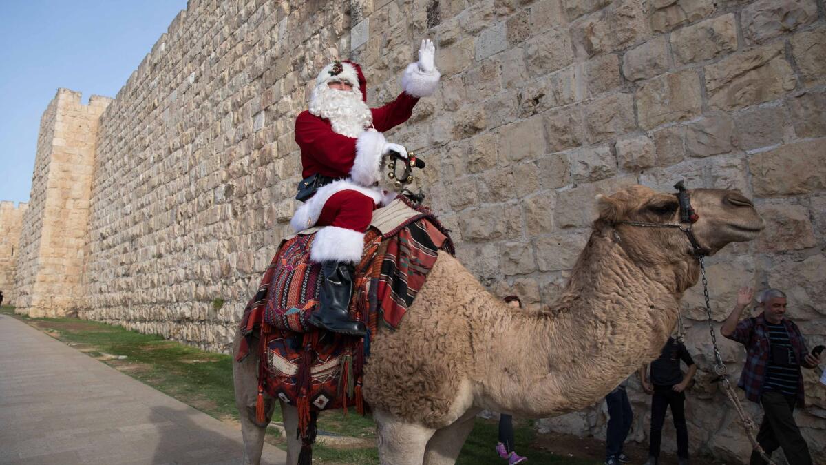 A Palestinian dressed in a Santa Claus costume rides a camel next to the walls of the Old City of Jerusalem on Dec. 21