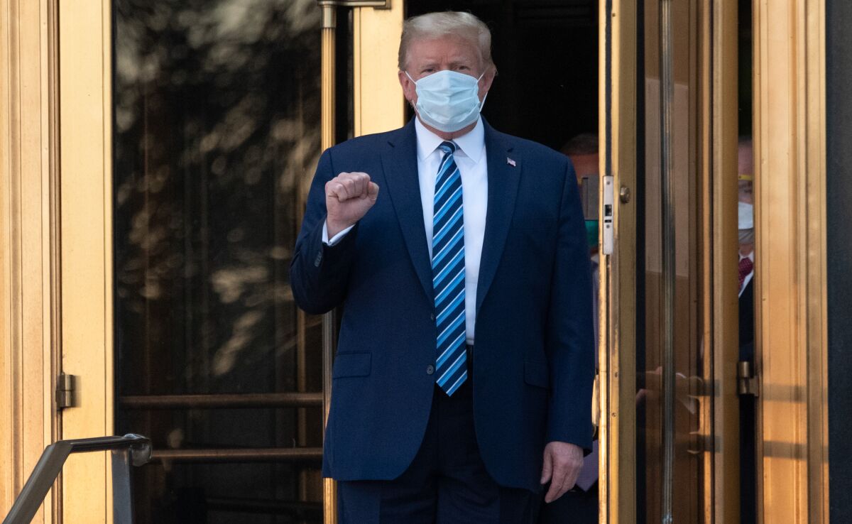 Trump holds up a clenched fist as he exits the hospital. 