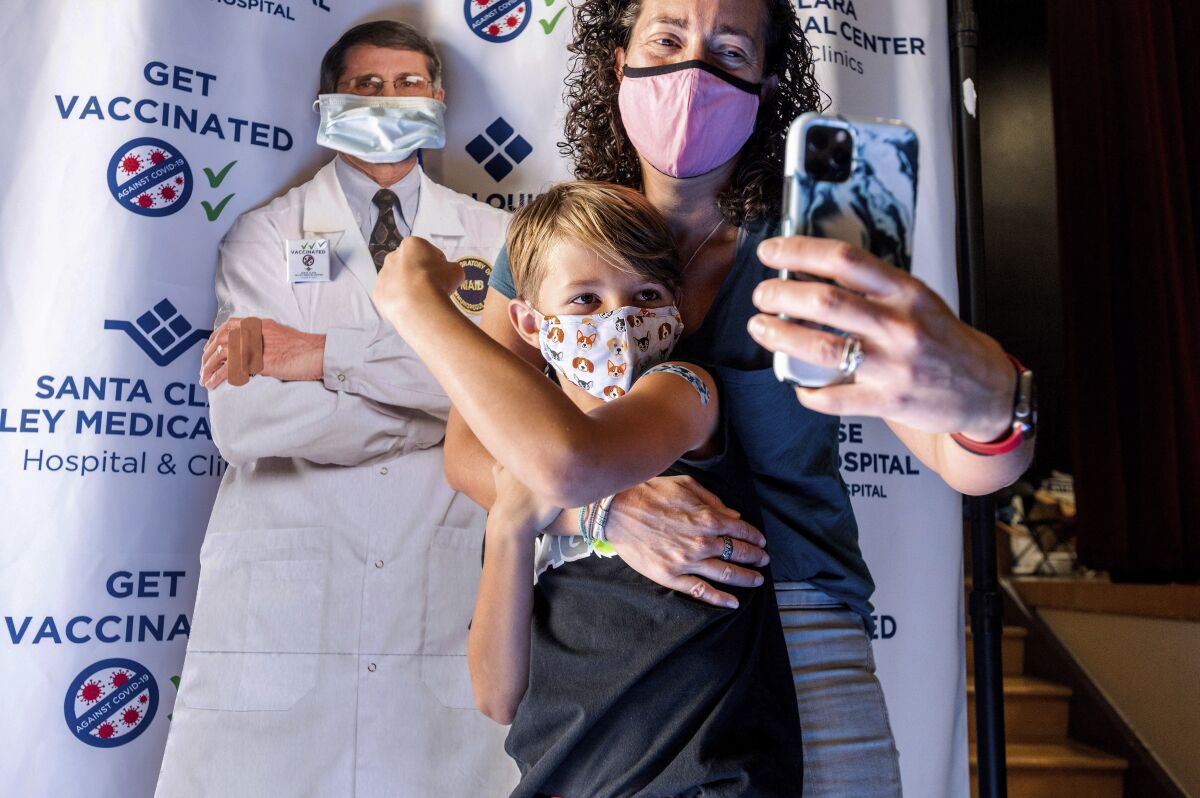 Finn Washburn, 9, shows his vaccination site as his mother, Kate Elsley, takes a photo shortly after he received a Pfizer-BioNTech COVID-19 vaccine in San Jose, Calif., on Wednesday, Nov. 3, 2021. The U.S. entered a new phase Wednesday in its COVID-19 vaccination campaign, with shots now available to millions of elementary-age children. (AP Photo/Noah Berger)