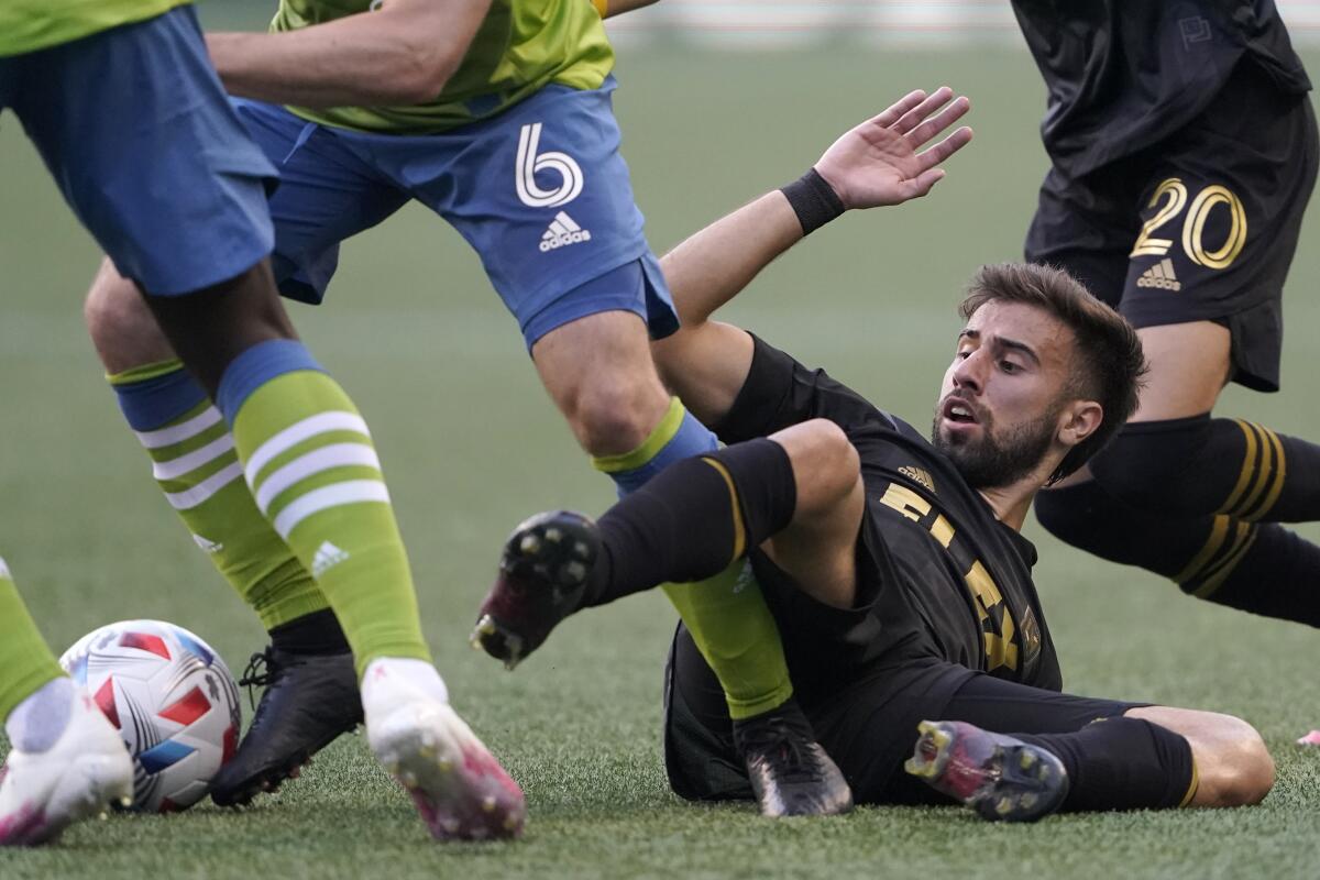 LAFC forward Diego Rossi is sprawled on the ground and battling to get to the ball during a match