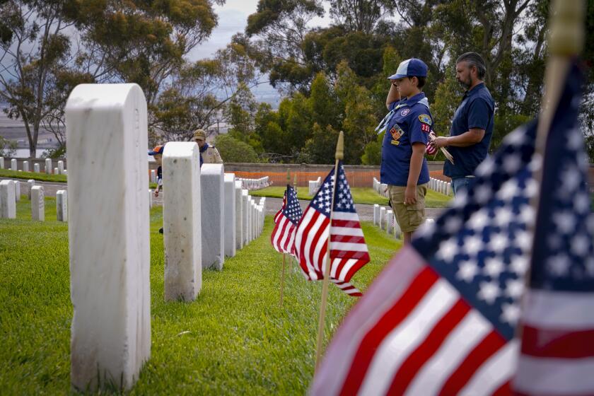San Diego, CA - May 28: On Saturday, May 28, 2022 in San Diego, CA., at Fort Rosecrans National Cemetery, Thomas Struck and his son, Gary Thomas Struck from Cub Scout Pack 395 said the names of each veteran out load as they placed a U.S. flag in each headstone for Memorial Day. The Strucks were among the hundreds of volunteers placing U.S. flags on each headstone for Memorial Day. (Nelvin C. Cepeda / The San Diego Union-Tribune)