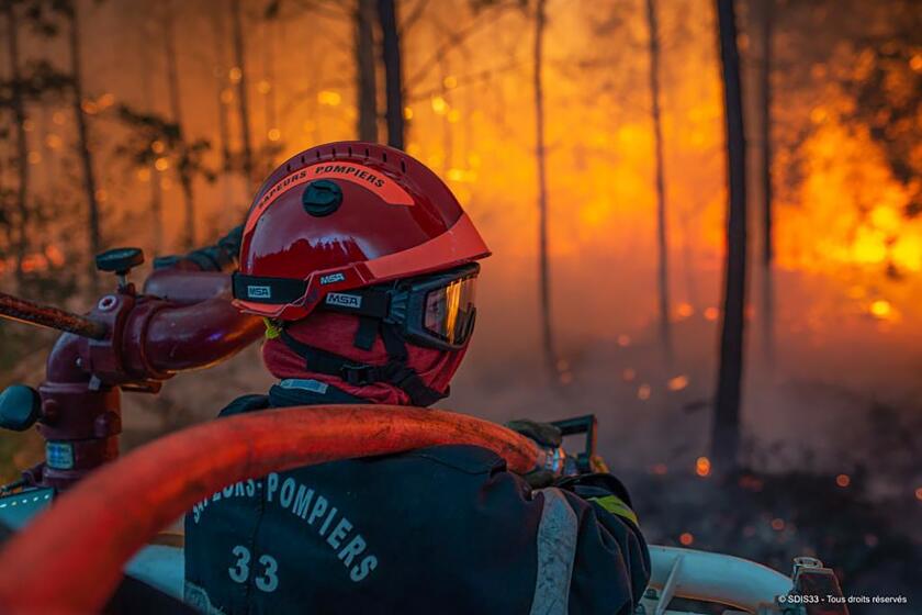 This photo provided by the fire brigade of the Gironde region (SDIS 33) shows a firefighter at work at a forest fire at La Test-de-Buch, southwestern France, late Monday, July 18, 2022. France scrambled more water-bombing planes and hundreds more firefighters to combat spreading wildfires that were being fed Monday by hot swirling winds from a searing heat wave broiling much of Europe. (SDIS 33 via AP)