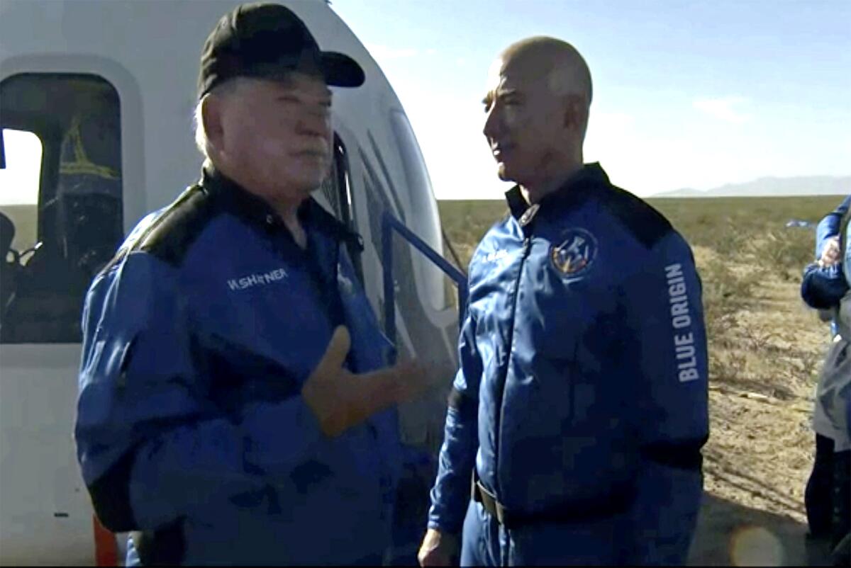William Shatner talks with Jeff Bezos next to a space capsule