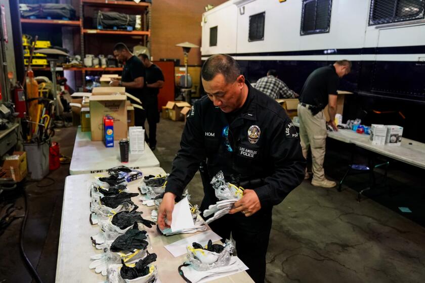 LOS ANGELES, CA - MARCH 11: Lt. Jay Hom, helps assemble kits consisting of an N95 mask, work gloves, and nitrile gloves, as he and other LAPD personnel assemble personal safety kits for field officers to protect themselves from exposure to the Coronavirus, at Piper Technical Center on Wednesday, March 11, 2020 in Los Angeles, CA. (Kent Nishimura / Los Angeles Times)