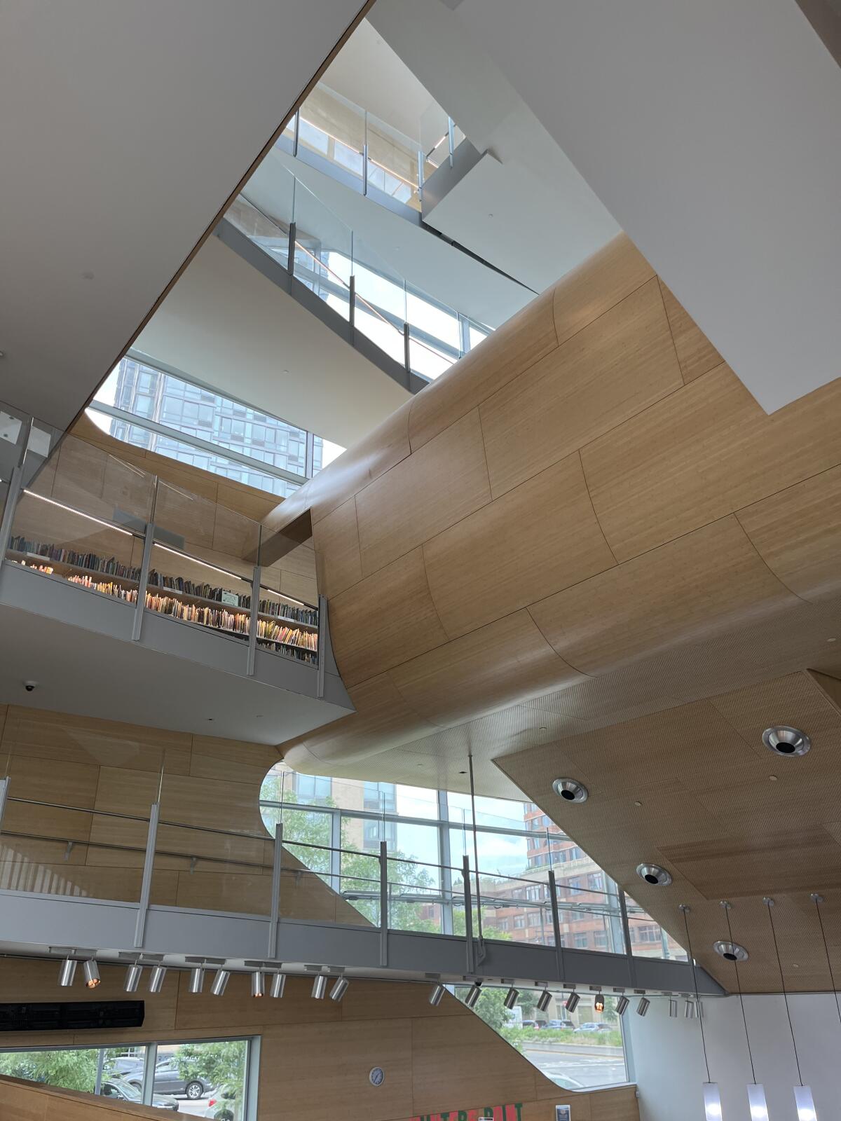 An upward view of a wood-lined atrium sows daylight pouring through windows on several floors