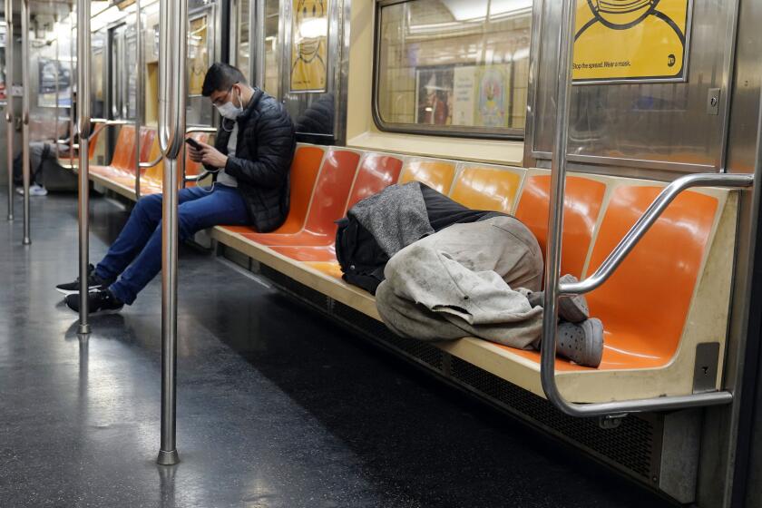 FILE - A man sleeps on subway train seats, in New York, on April 14, 2021.New York Mayor Eric Adams is announcing a plan to boost safety in the city's sprawling subway network and try to stop homeless people from sleeping on trains or living in stations. (AP Photo/Richard Drew, File)