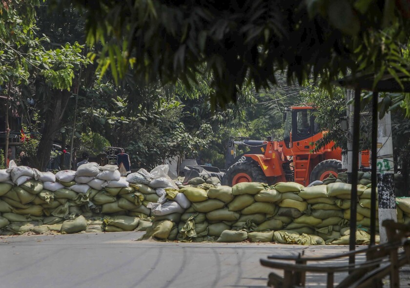 An orange bulldozer sits amid a makeshift barricade of sandbags 