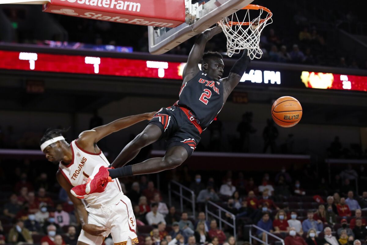 Utah guard Both Gach, right, dunks against Southern California forward Chevez Goodwin during the first half of an NCAA college basketball game in Los Angeles, Wednesday, Dec. 1, 2021. (AP Photo/Alex Gallardo)