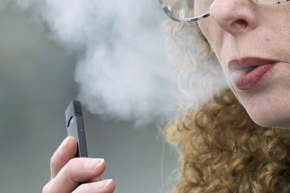A woman exhales while vaping from a Juul pen e-cigarette in Vancouver, Wash. On Wednesday, Feb. 12, 2020. 