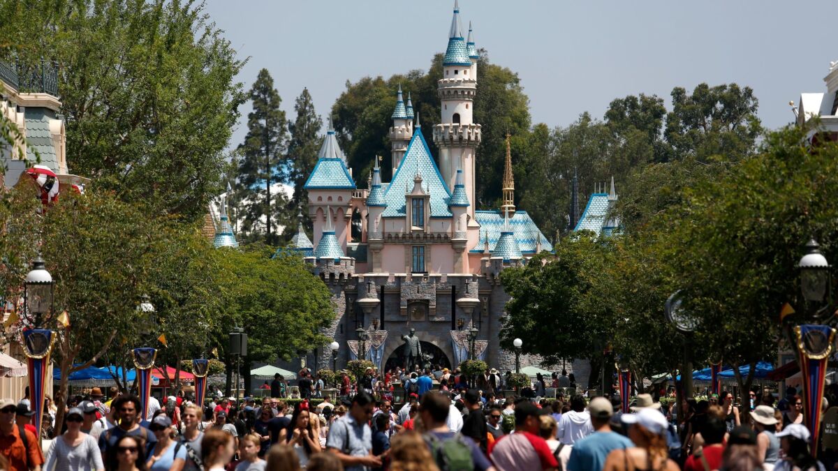 A study found that 73% of workers who were surveyed said they don't earn enough to pay for basic living expenses. Above, guests crowd Main Street in front of Sleeping Beauty Castle at Disneyland in June 2017.
