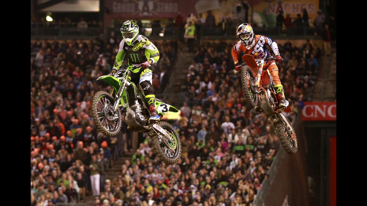 Eli Tomac, left, who took first in the heat, and Dean Wilson soar over a jump on his way to taking first place in the 450SX heat 1 of the Monster Energy AMA Supercross race at Angel Stadium on Jan. 9.