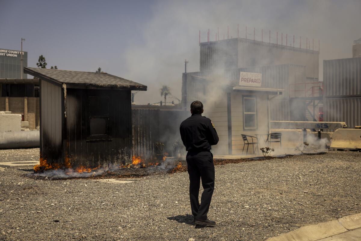 A firefighter watched a demonstration burning house to show the effectiveness of preventing embers.