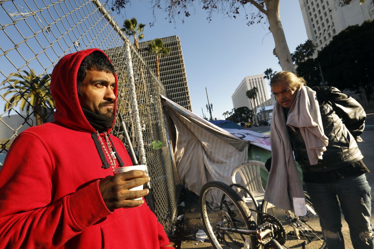Luis Suarez, left, waits for the cleanup to start on Spring Street across from City Hall.