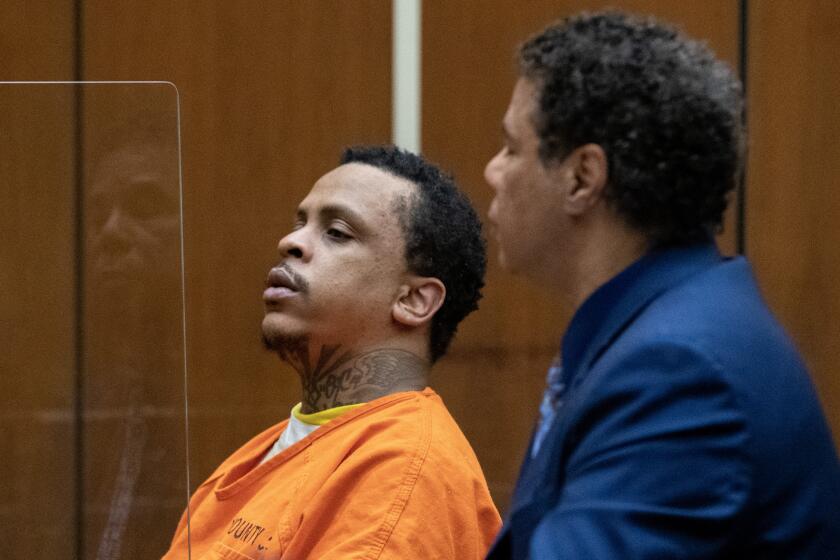 Eric Holder Jr., left, listens during his sentencing proceeding for the murder of Nipsey Hussle in Superior Court. 