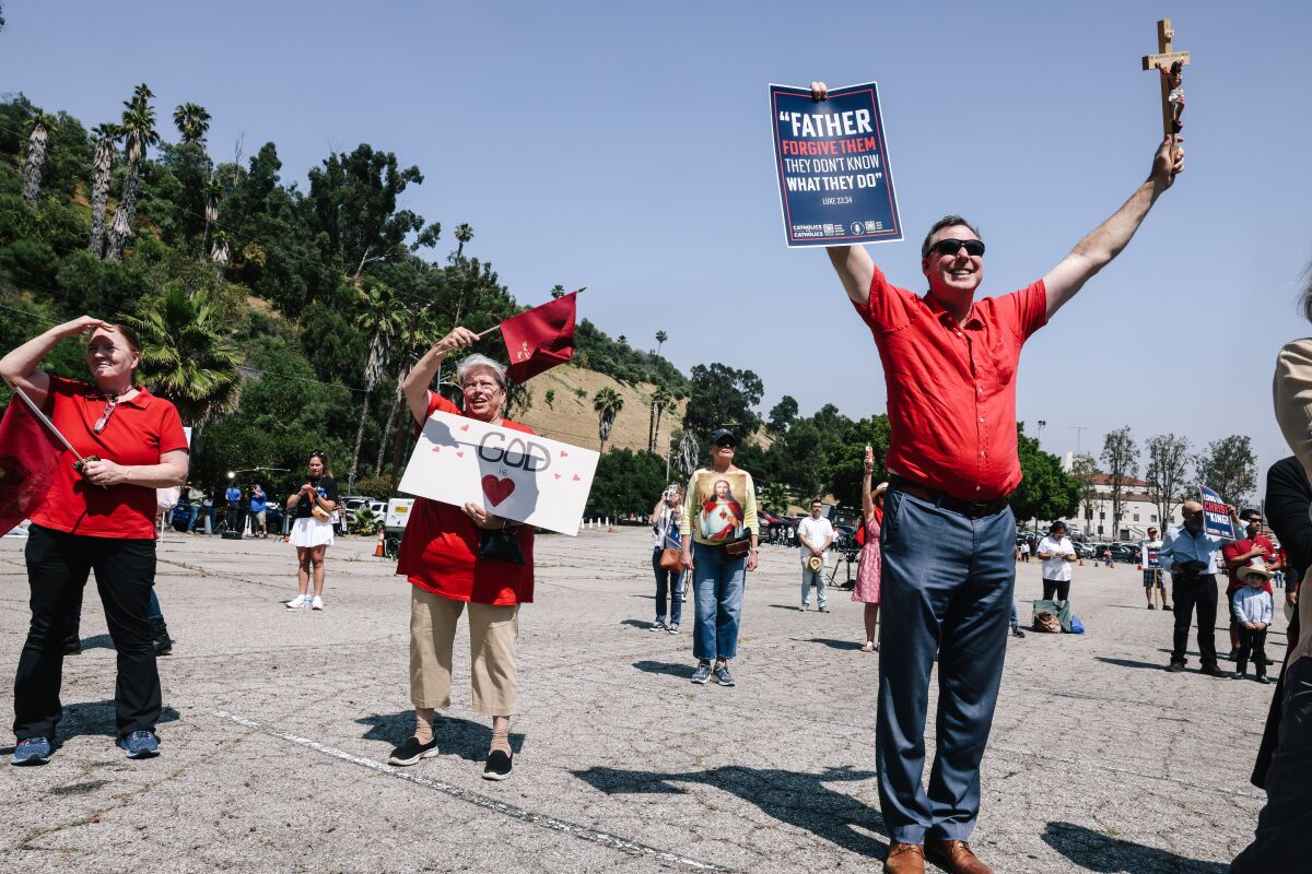 Melody Meyer, second from left, holds a "God is Love" sign during a protest in a parking lot outside Dodger Stadium.