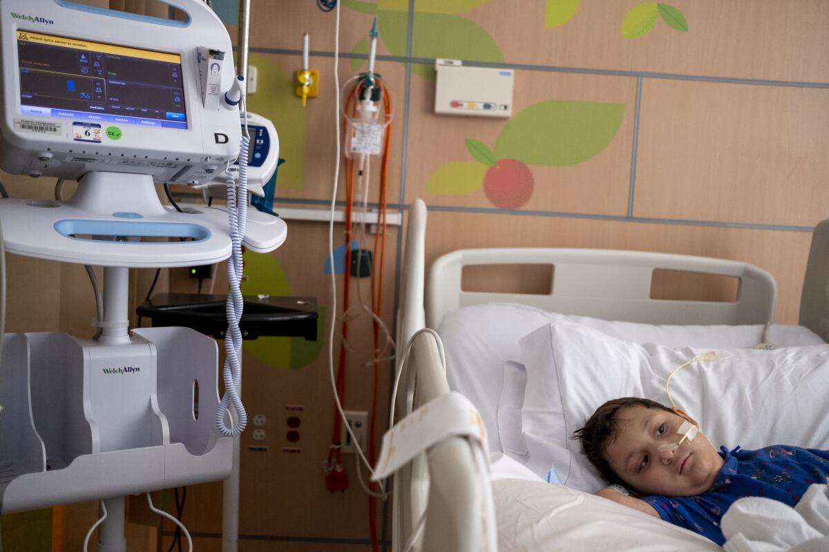 A 5-year-old in a hospital bed with equipment nearby and a tube connected to his nose
