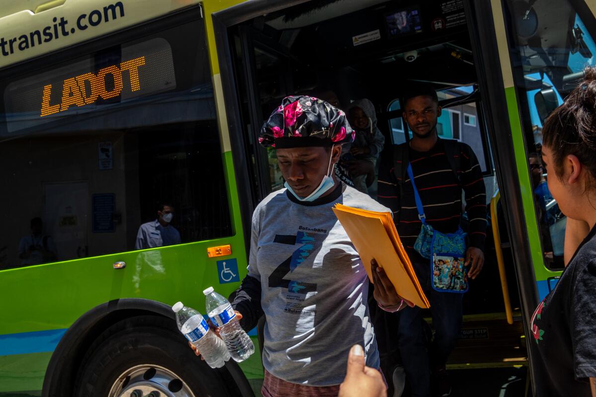 A man wearing a bicycle helmet exits a bus