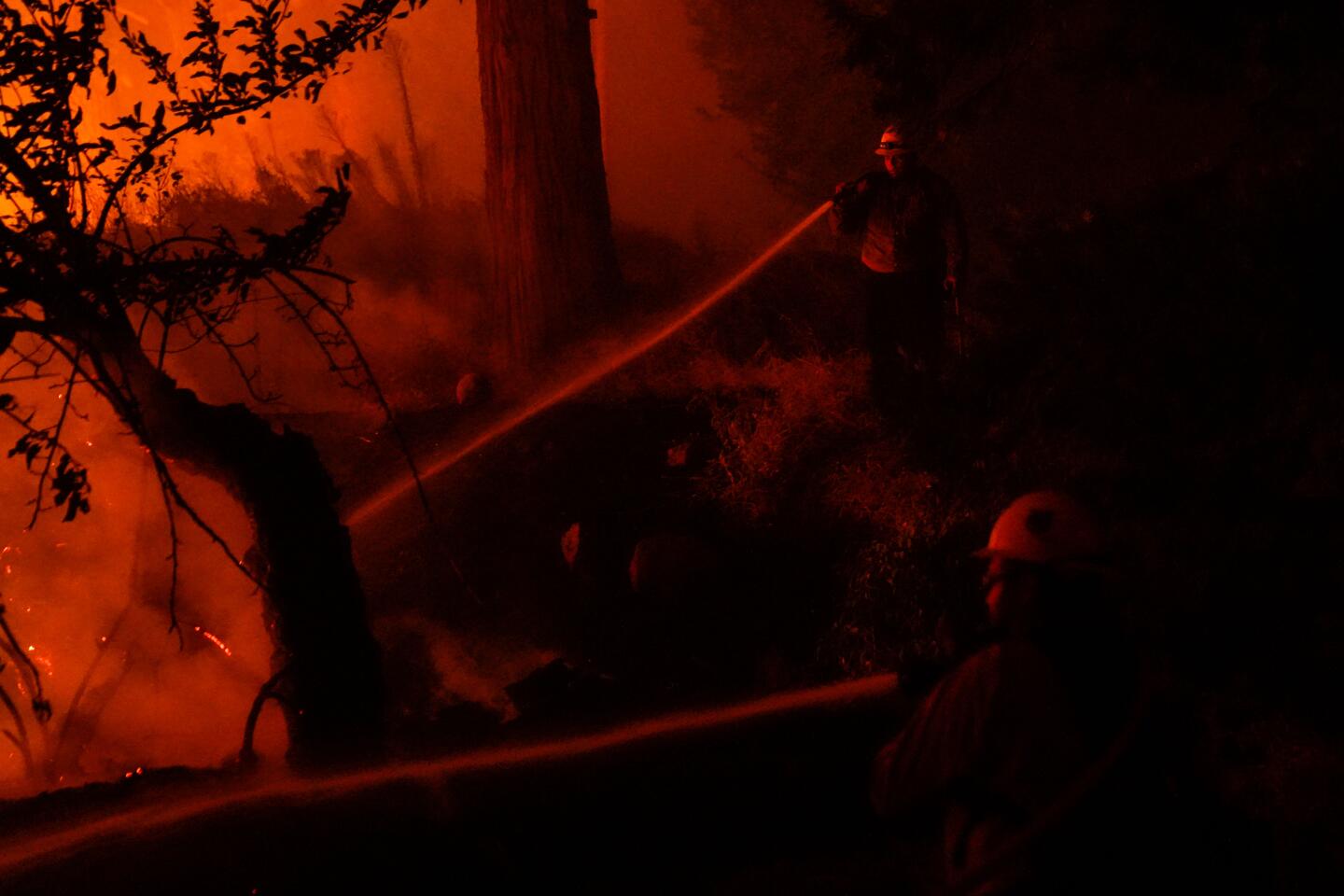 A firefighter sprays a hose during the Creek fire.