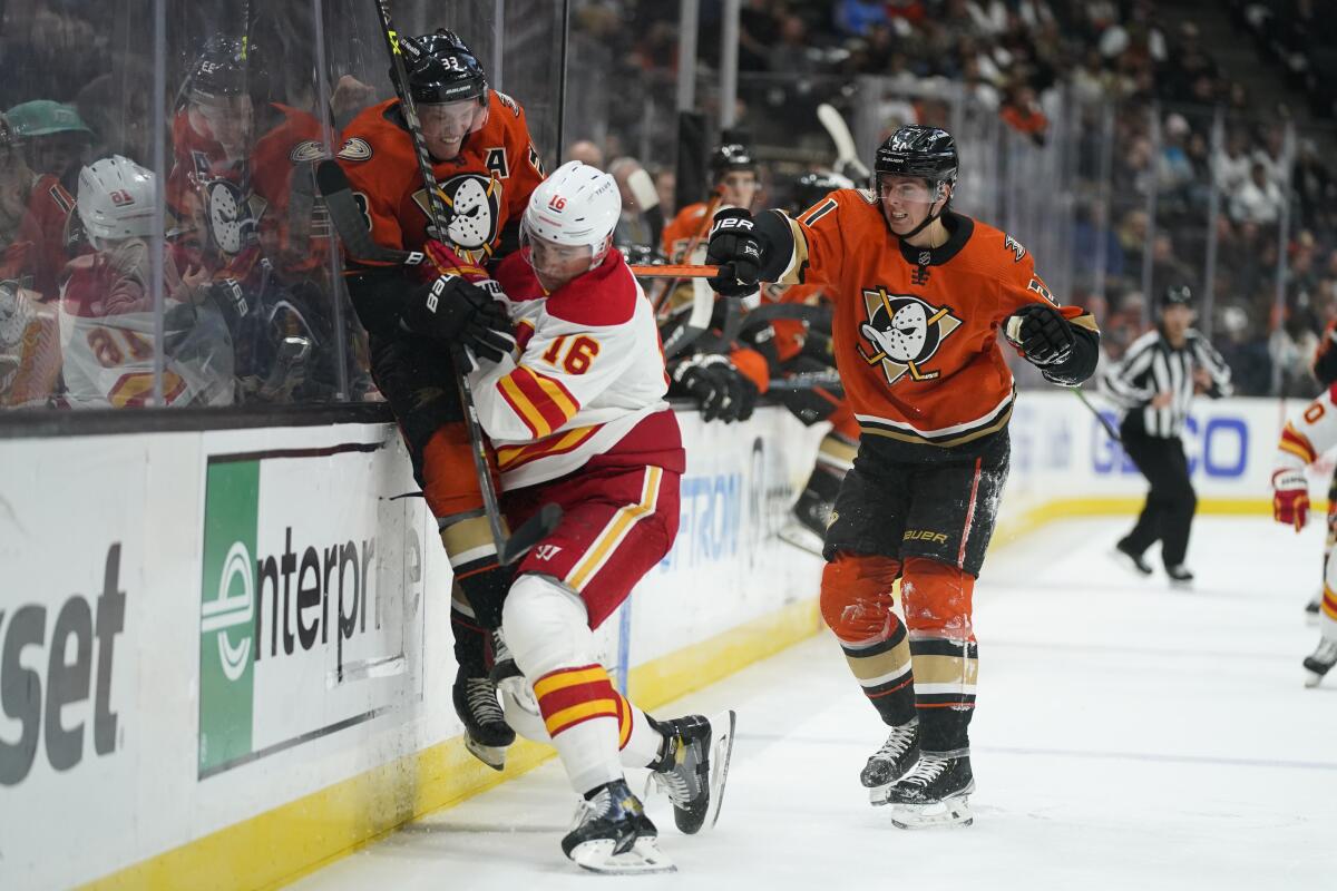 Flames defenseman Nikita Zadorov checks Ducks forward Jakob Silfverberg as Isac Lundestrom trails the play.