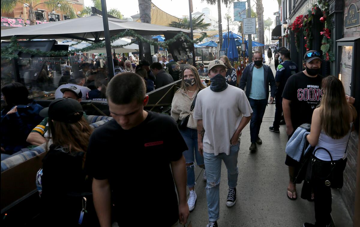 Shoppers and diners, both masked and unmasked, crowd Main Street in Huntington Beach on Dec. 6, 2020.