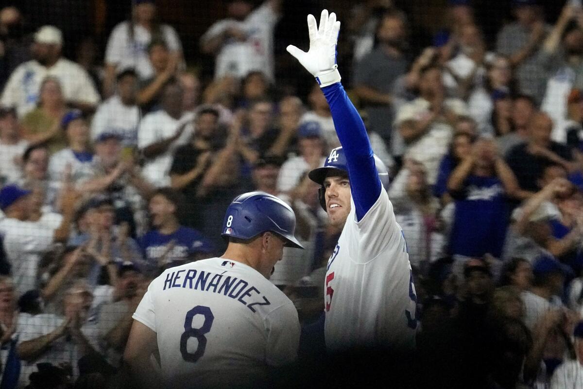Dodgers' Freddie Freeman waves after hitting a two-run home run as Kiké Hernández stands by.