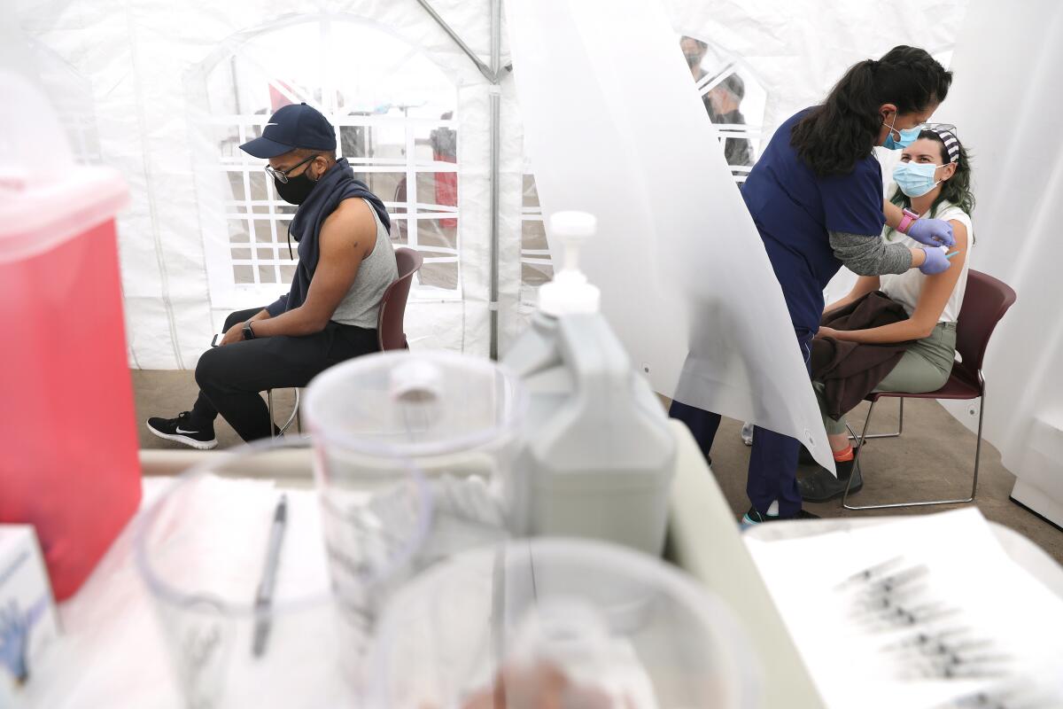 Two people in chairs separated by plastic barriers