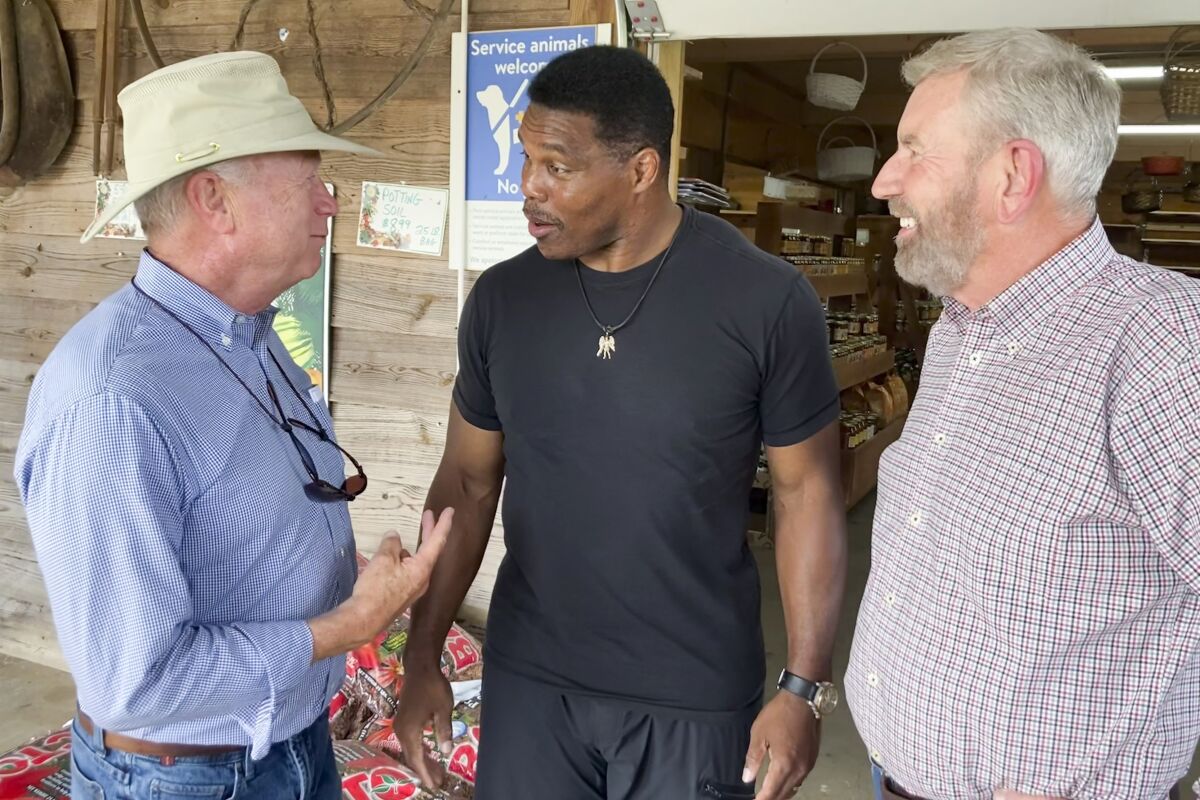 FILE - Republicans U.S. Senate candidate Herschel Walker, center, talks with Georgia state Sen. Butch Miller, left, and former state Rep. Terry Rogers as Walker campaigns on July 21, 2022, in Alto, Ga. Democratic incumbent Sen. Raphael Warnock has committed to three debates with Walker, but Walker has now chosen a separate, fourth debate before the November election. (AP Photo/Bill Barrow, File)