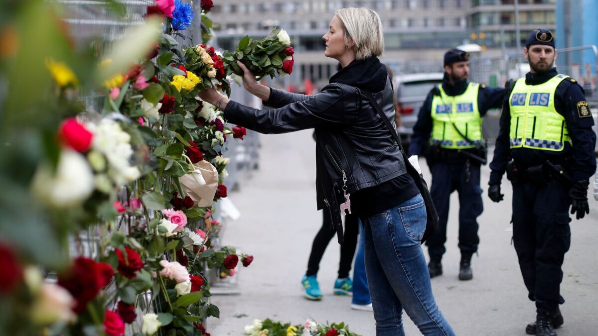 A woman places flowers on a fence Saturday following a truck attack in central Stockholm.