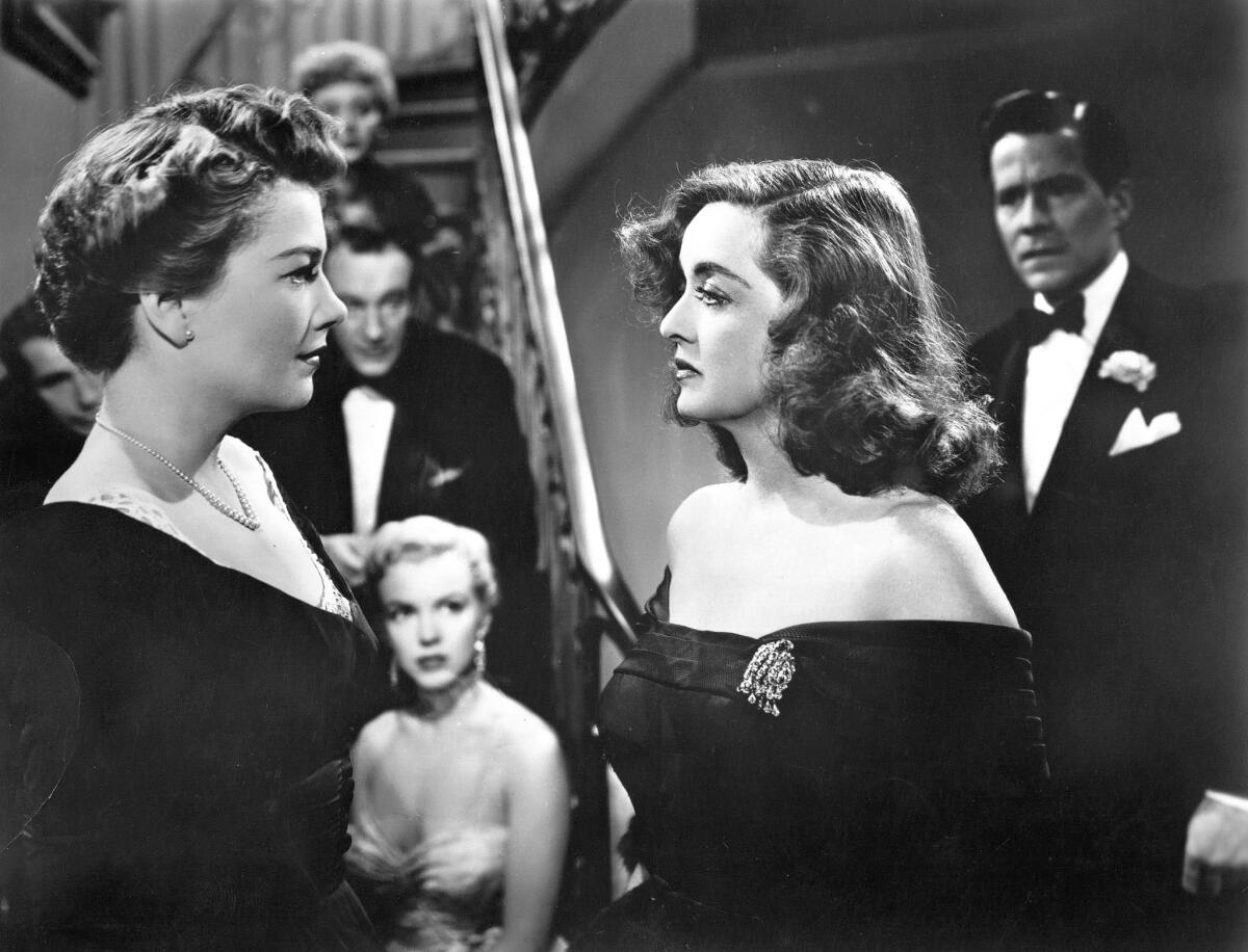 Anne Baxter, left, faces Bette Davis as Marilyn Monroe watches from the stairs in "All About Eve."