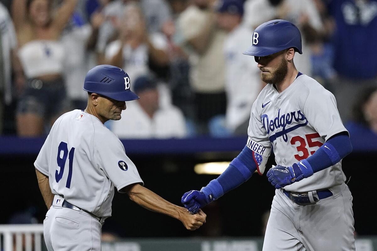 Los Angeles Dodgers' Cody Bellinger (35) celebrates with third base coach Dino Ebel (91) after hitting a solo home run during the ninth inning of a baseball game against the Kansas City Royals Saturday, Aug. 13, 2022, in Kansas City, Mo. The Dodgers won 13-3. (AP Photo/Charlie Riedel)