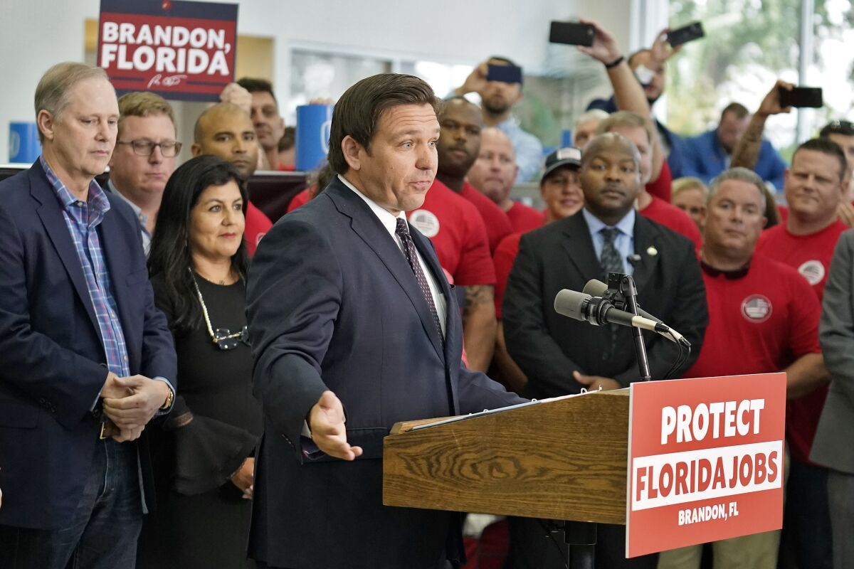 Florida Gov. Ron DeSantis speaks from behind a lectern surrounded by supporters