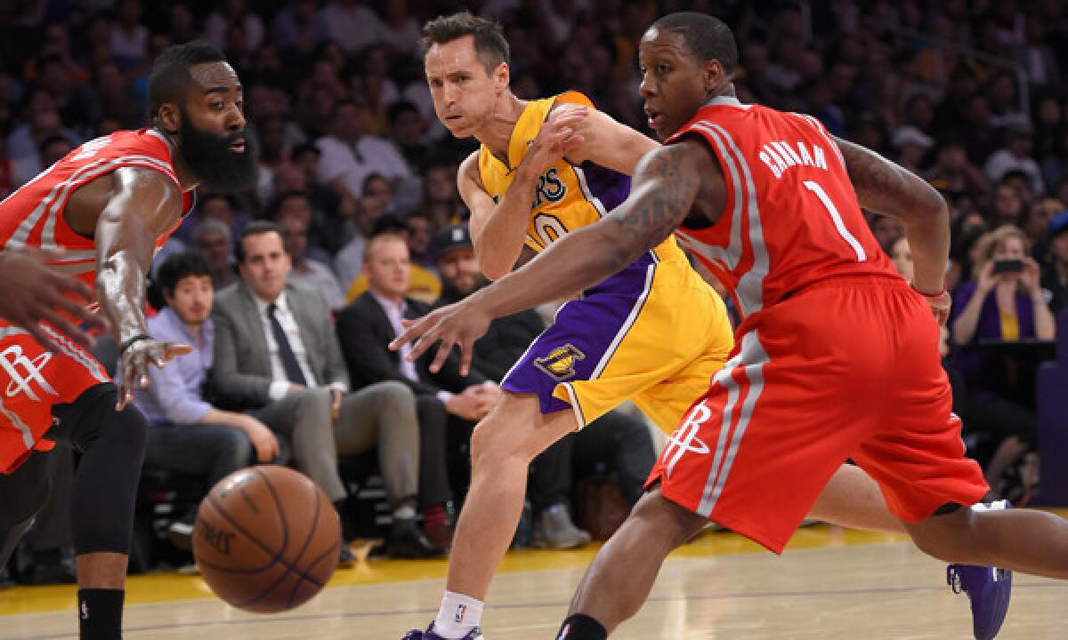 Lakers point guard Steve Nash, center, passes between Houston Rockets teammates James Harden, left, and Isaiah Canaan during the first half of the Lakers' 145-130 loss Tuesday at Staples Center.