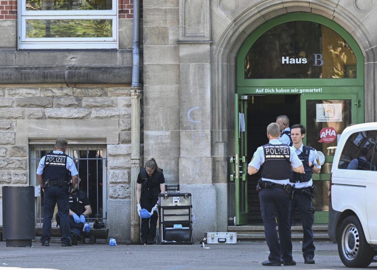 Police officers secure a crime scene in front of a school in Esslingen, Germany, Friday, June 10, 2022. A woman and a child were injured in a violent attack at an elementary school. (Bernd Weissbrod/dpa via AP)