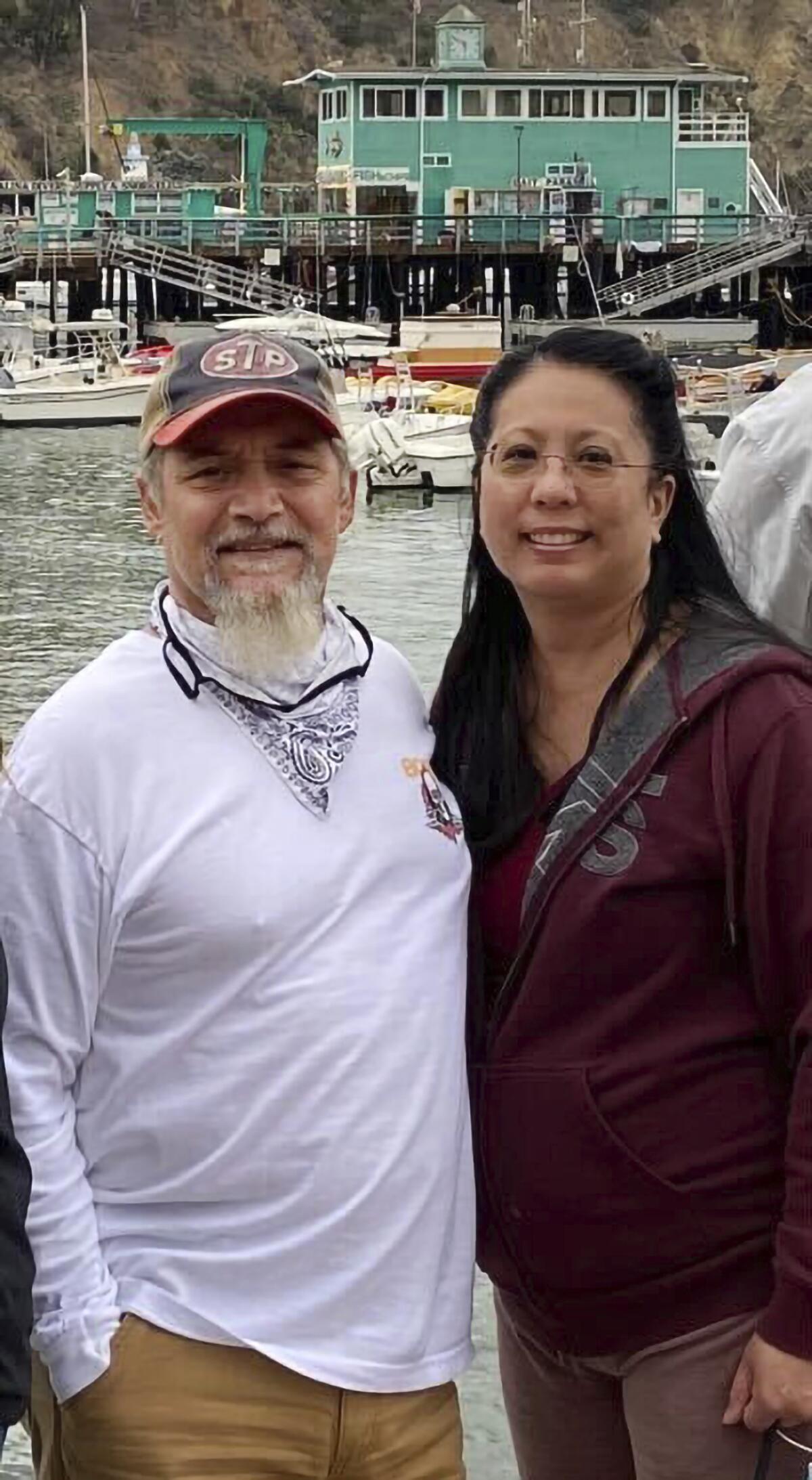 A couple stand before boats on a body of water