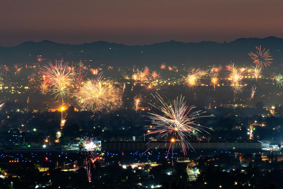 Fireworks explode in the night sky over an urban area