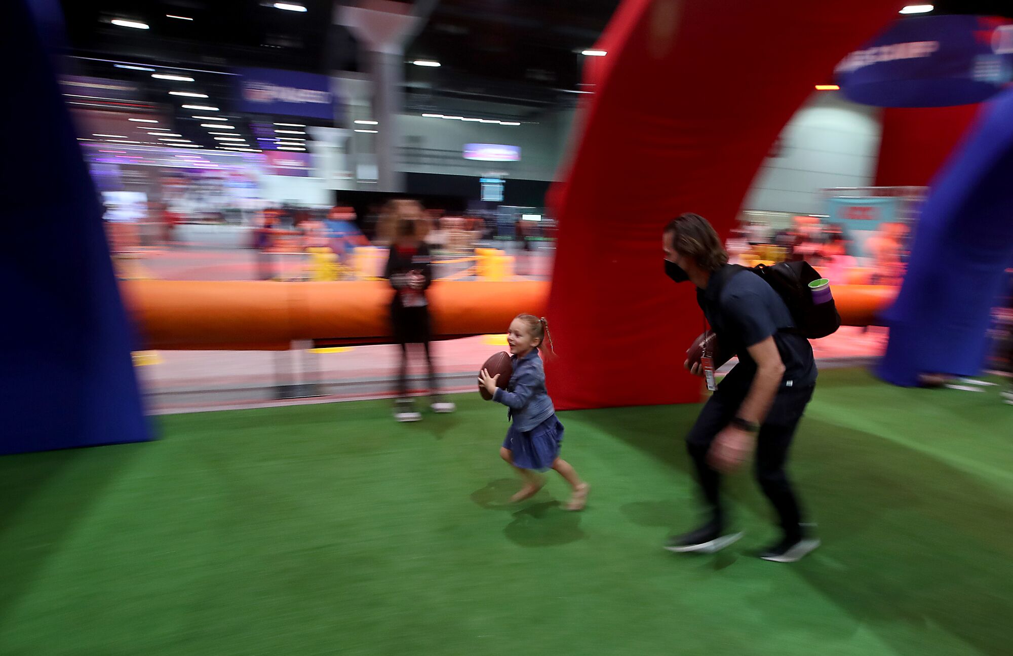 A child runs with a football at the Super Bowl Experience at the L.A. Convention Center.