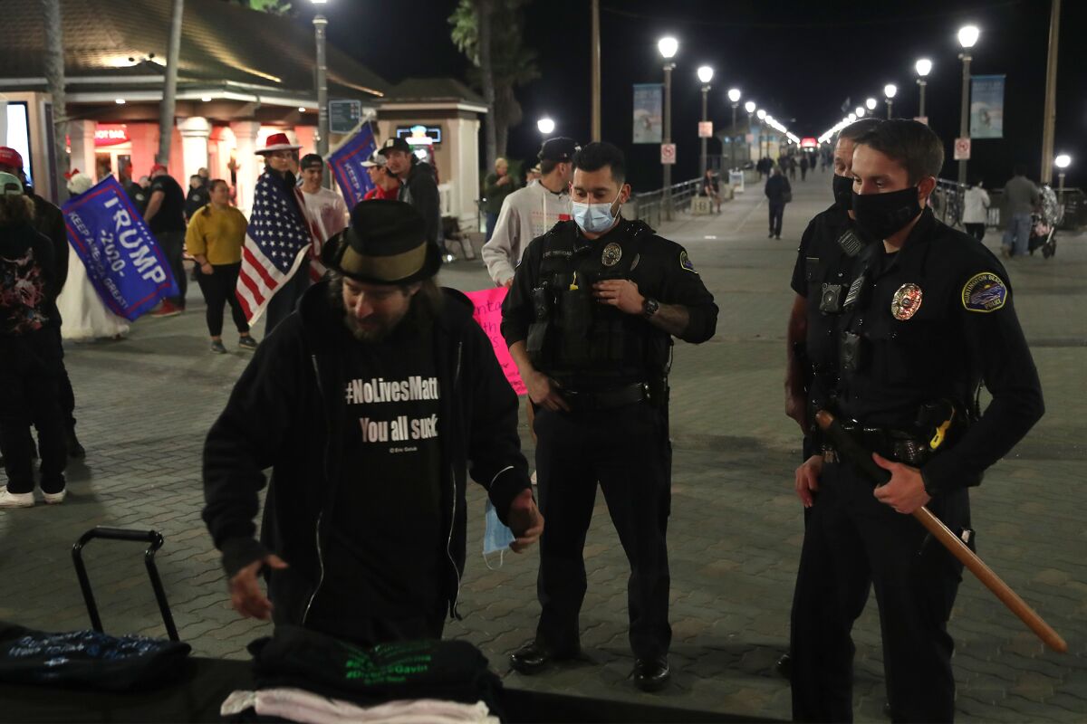 Huntington Beach police officers let a man selling T-shirts know he cannot set up in this spot.