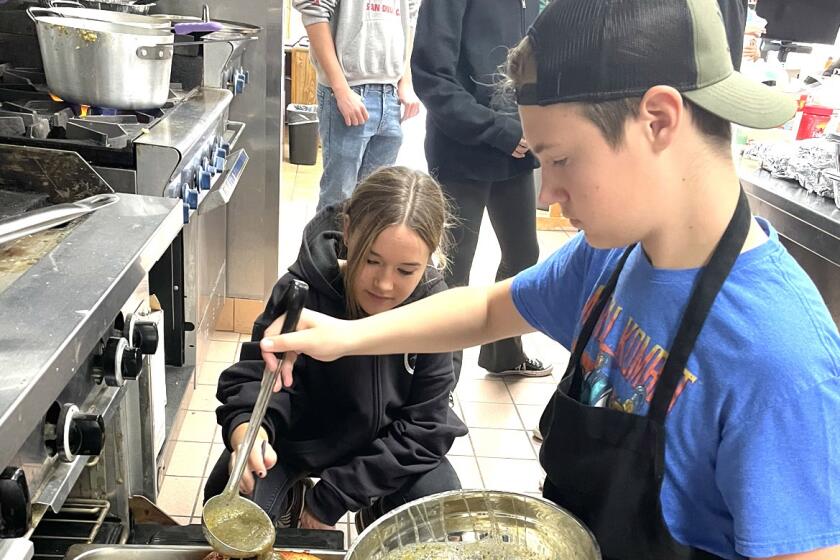 Alexia Matthes, left, and Ryan Fox baste a turkey for Thanksgiving as part of the Ramona High School culinary arts program. 