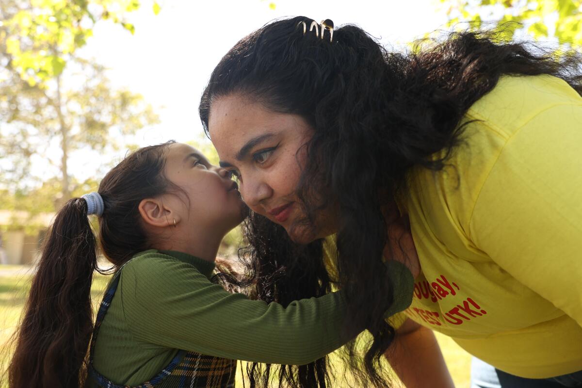 A 4-year-old girl whispers to her mother while at the park.