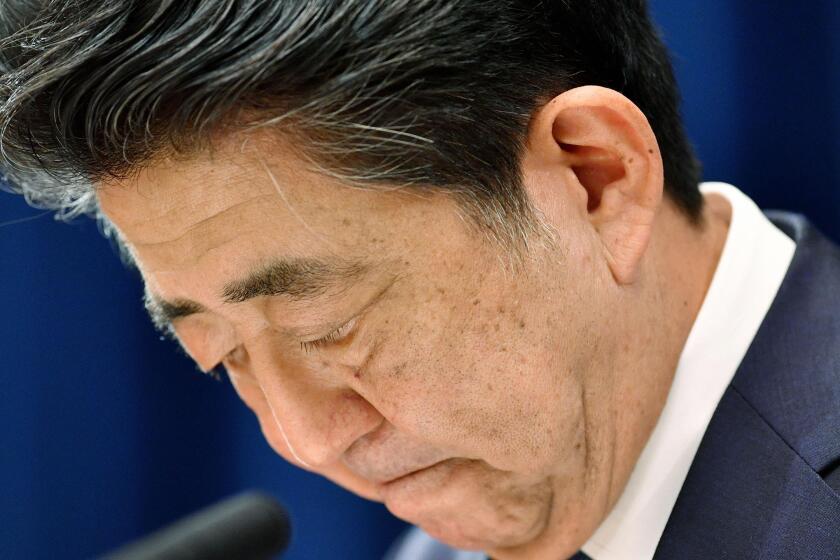 Japanese Prime Minister Shinzo Abe downs his head as he says he is stepping down during a press conference at the prime minister official residence in Tokyo Friday, Aug. 28, 2020. Japan's longest-serving prime minister Abe said Friday he intends to step down because a chronic health problem has resurfaced. He told reporters that it was “gut wrenching” to leave so many of his goals unfinished. (Kyodo News via AP)