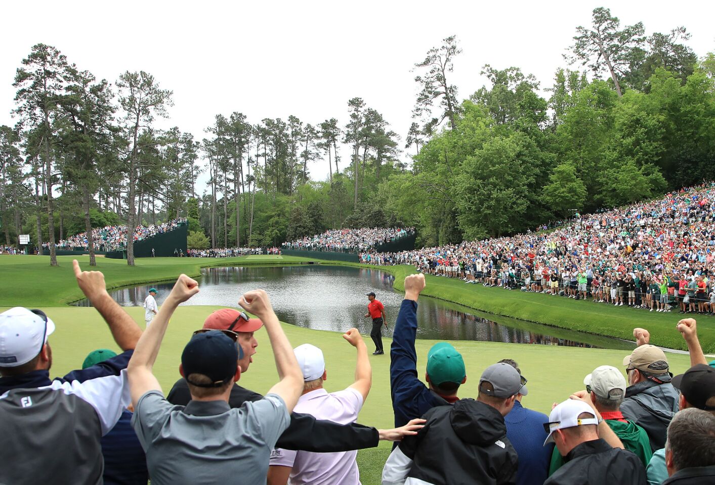 Patrons cheer as Tiger Woods celebrates his birdie on the 16th green during the final round of the Masters on Sunday at Augusta National Golf Club in Augusta, Ga.