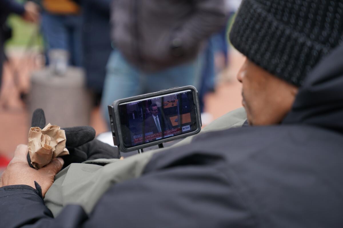 A man watches closing arguments on a small screen 