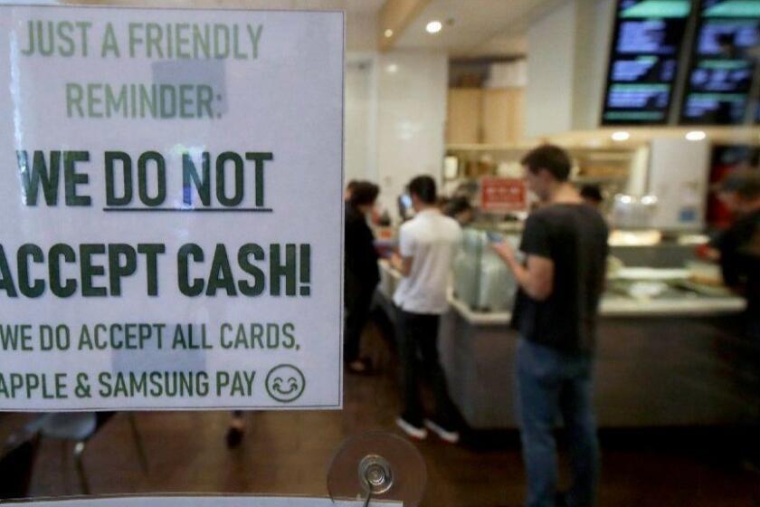 This Thursday, May 2, 2019, photo shows a sign posted on a door alerting customers that cash is not accepted at Freshroll Vietnamese Rolls & Bowls in San Francisco. San Francisco is about to require brick-and-mortar retailers to take cash in payment for goods, joining Philadelphia and New Jersey in banning a practice that critics say discriminates against the poor. (AP Photo/Jeff Chiu)