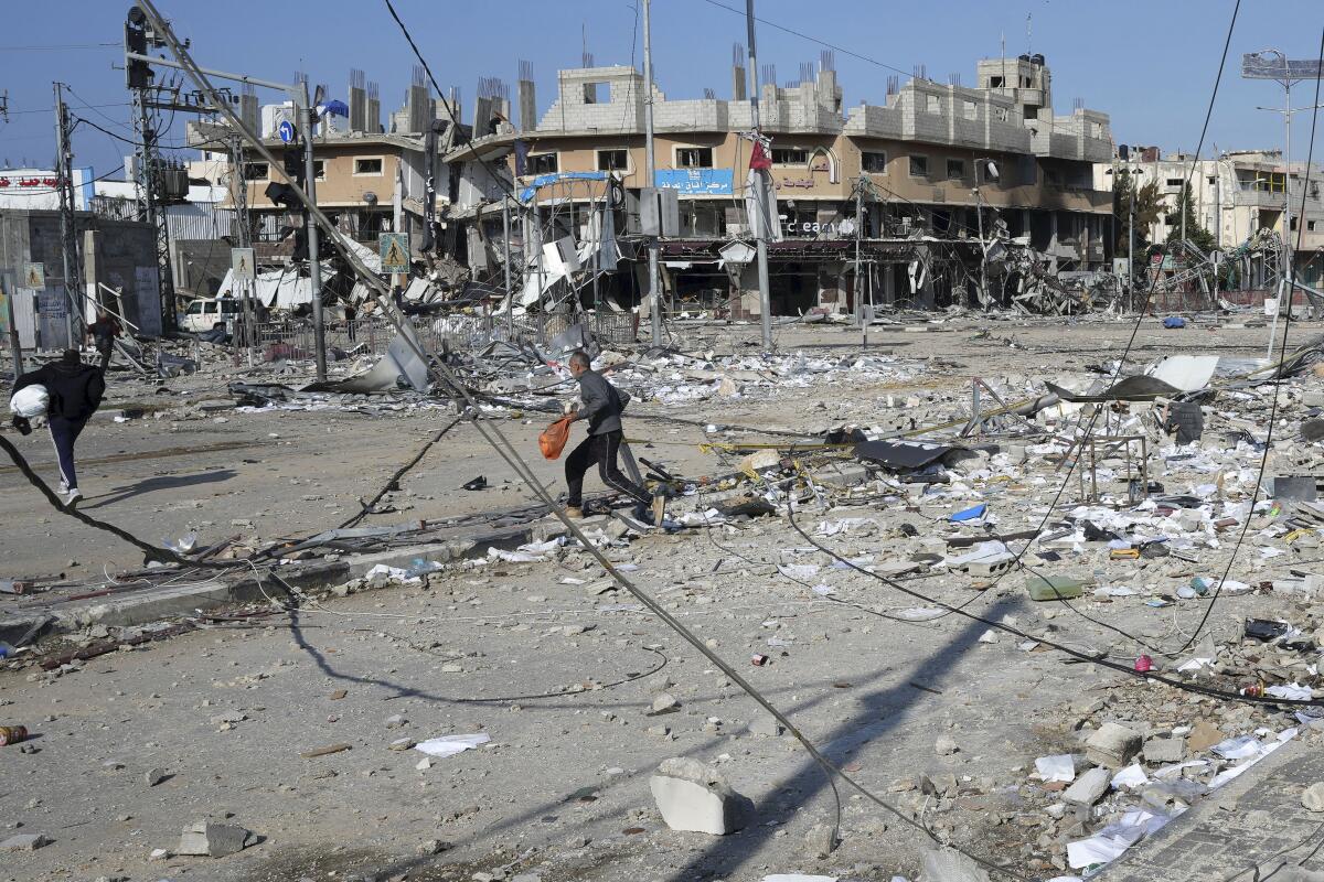 Palestinians walk through destruction caused by Israeli bombardment 